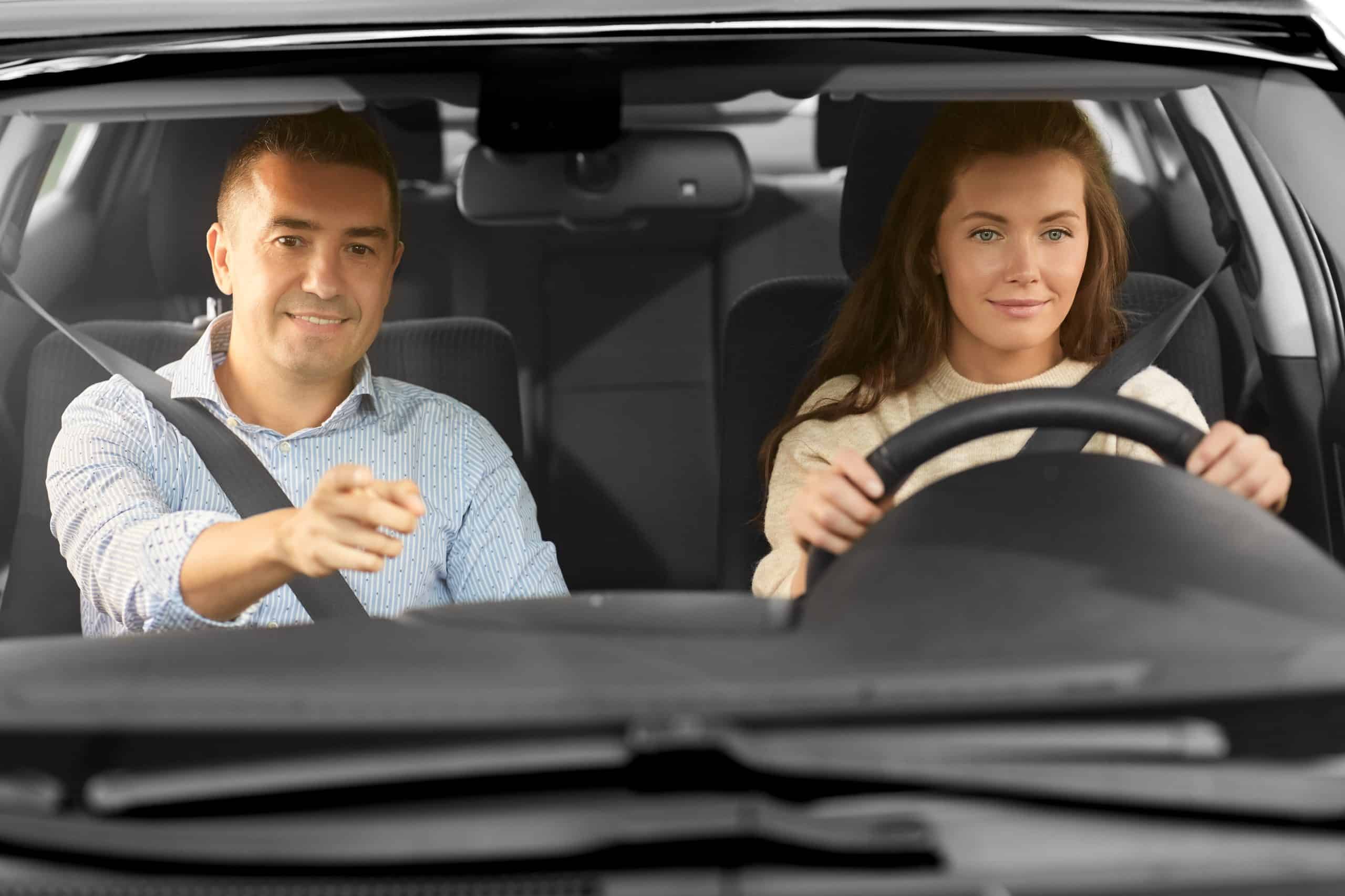 Driving instructor teaching adult woman how to drive